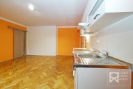 Obývací pokoj s kuchyňskou linkou + vchod šoupacími dveřmi do další místnosti